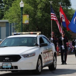 carl junction police cruiser driving down road in parade with flags presented behind it